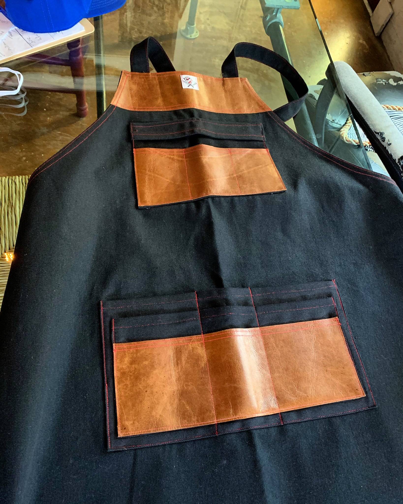 “My name is Sue, How do you do” Black denim & cognac leather crossback apron